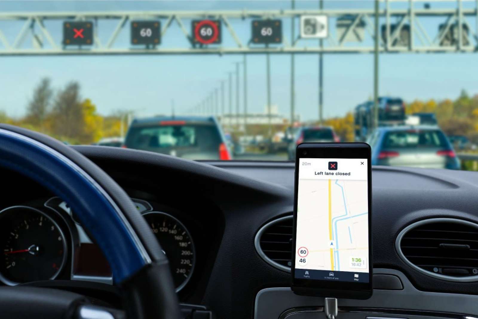 Smartphone in a car mount showing a highway lane closure alert in the Flitsmeister app