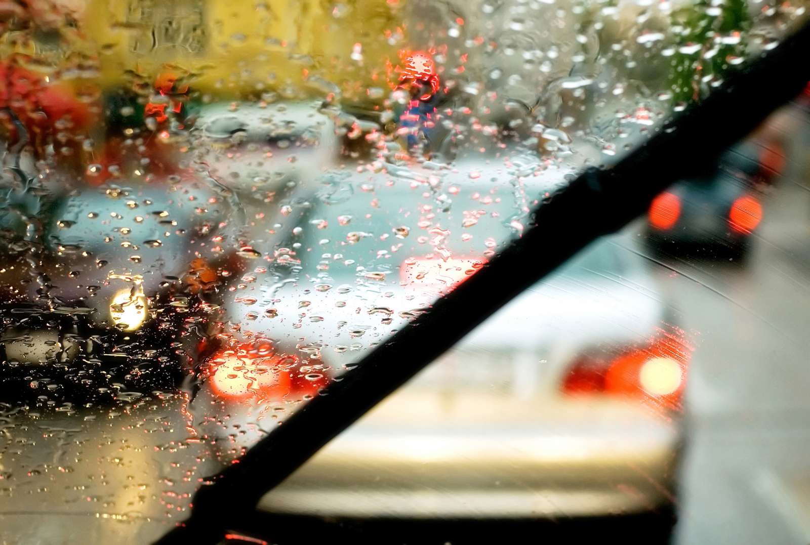 View through a rainy car windshield with blurred tail lights in a traffic jam